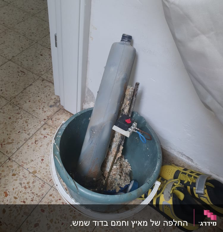 דלי עם כלים וחלקי צנרת ליד נעליים